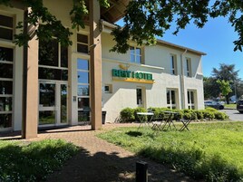 Un bâtiment d'hôtel avec une enseigne indiquant « BRIT HOTEL » et une zone d'entrée pavée avec des sièges extérieurs.