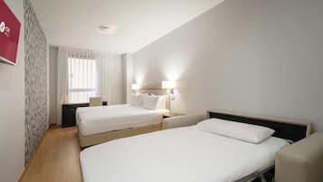 Habitació d'hotel amb dos llits, una taula i una cadira.
