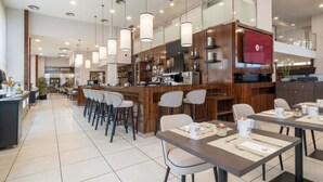 A modern restaurant with a bar area, high ceilings, and pendant lighting. - Exe Convention Plaza Madrid (Madrid)