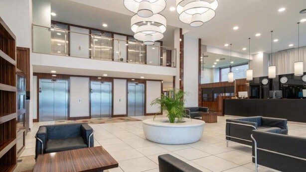A spacious lobby with a modern design, featuring a reception desk, seating areas, and a staircase to an upper level. - Exe Convention Plaza Madrid (Madrid)