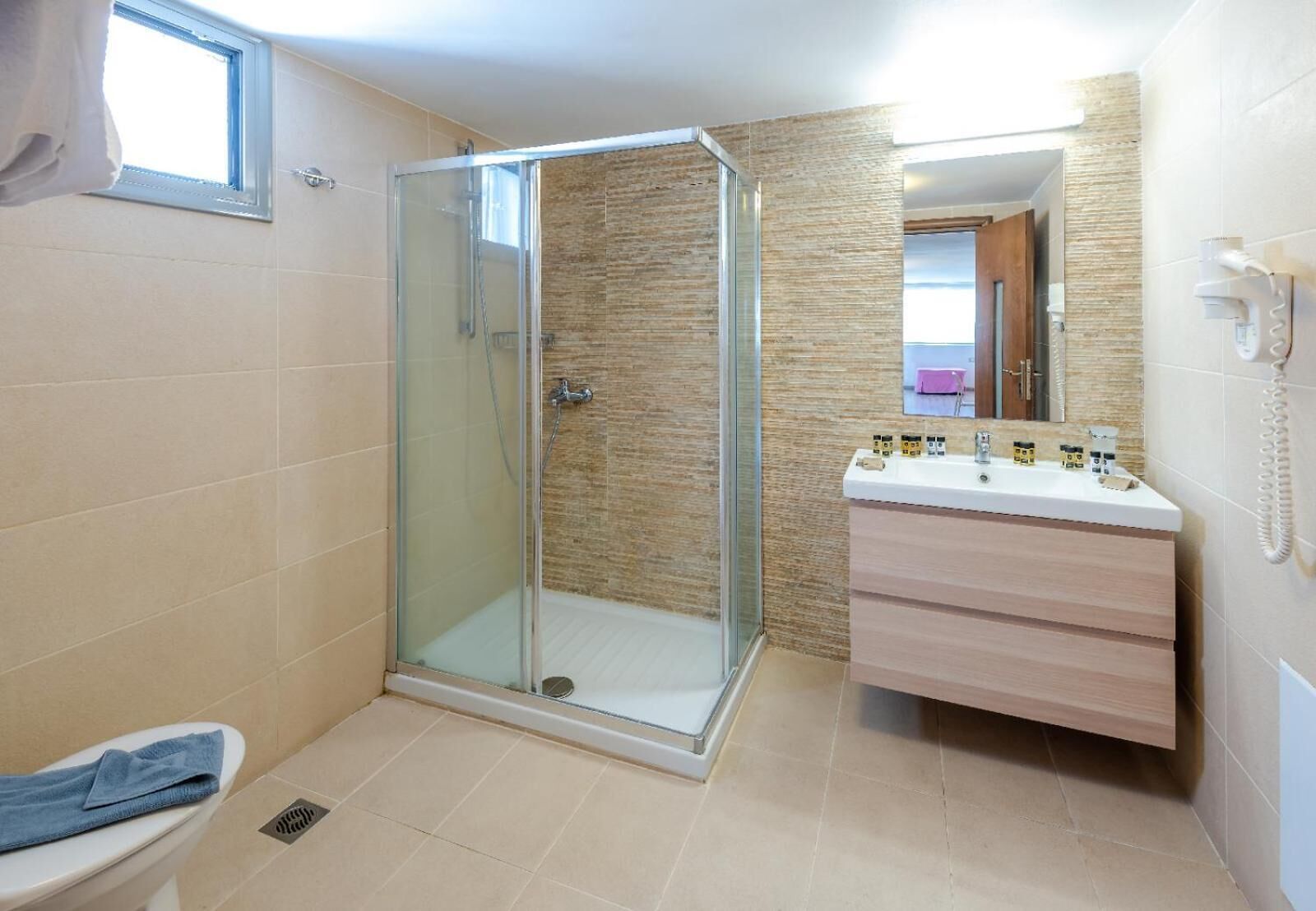 Ein Badezimmer mit einer gläsernen Duschkabine, einer Toilette und einem Waschtisch mit Spiegel.