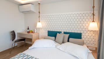 Une chambre d’hôtel avec un lit, un bureau et une chaise. Il y a un climatiseur fixé au mur et un panneau décoratif derrière le lit.