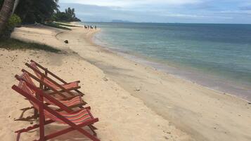 A beach with a row of wooden beach chairs and a sandy shoreline.