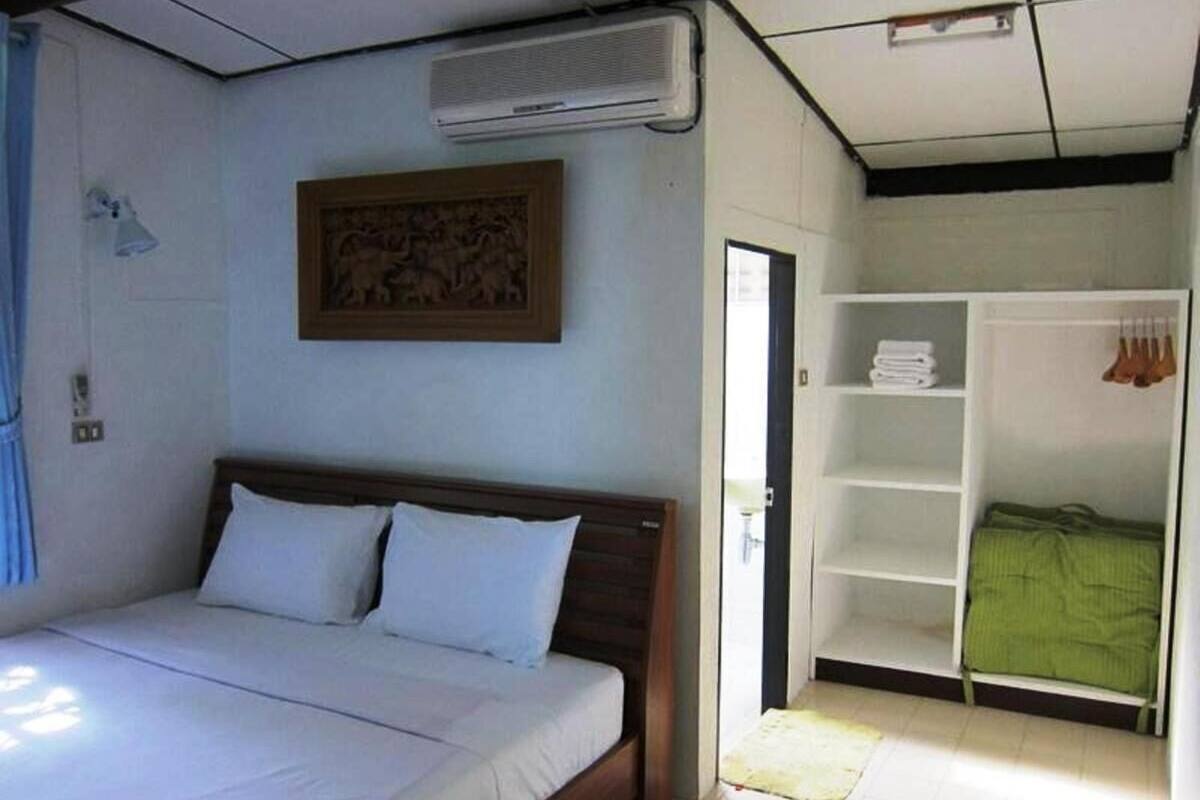 A bedroom with a bed, a wardrobe, and an air conditioning unit.