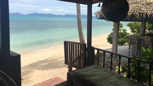 A beach view from a covered area with a wooden bench and a hanging light fixture. - Bang Po Village (Koh Samui)