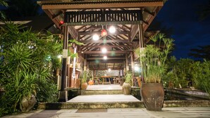 A covered outdoor area with a wooden structure, seating, and potted plants. - Am Samui Resort (Koh Samui)