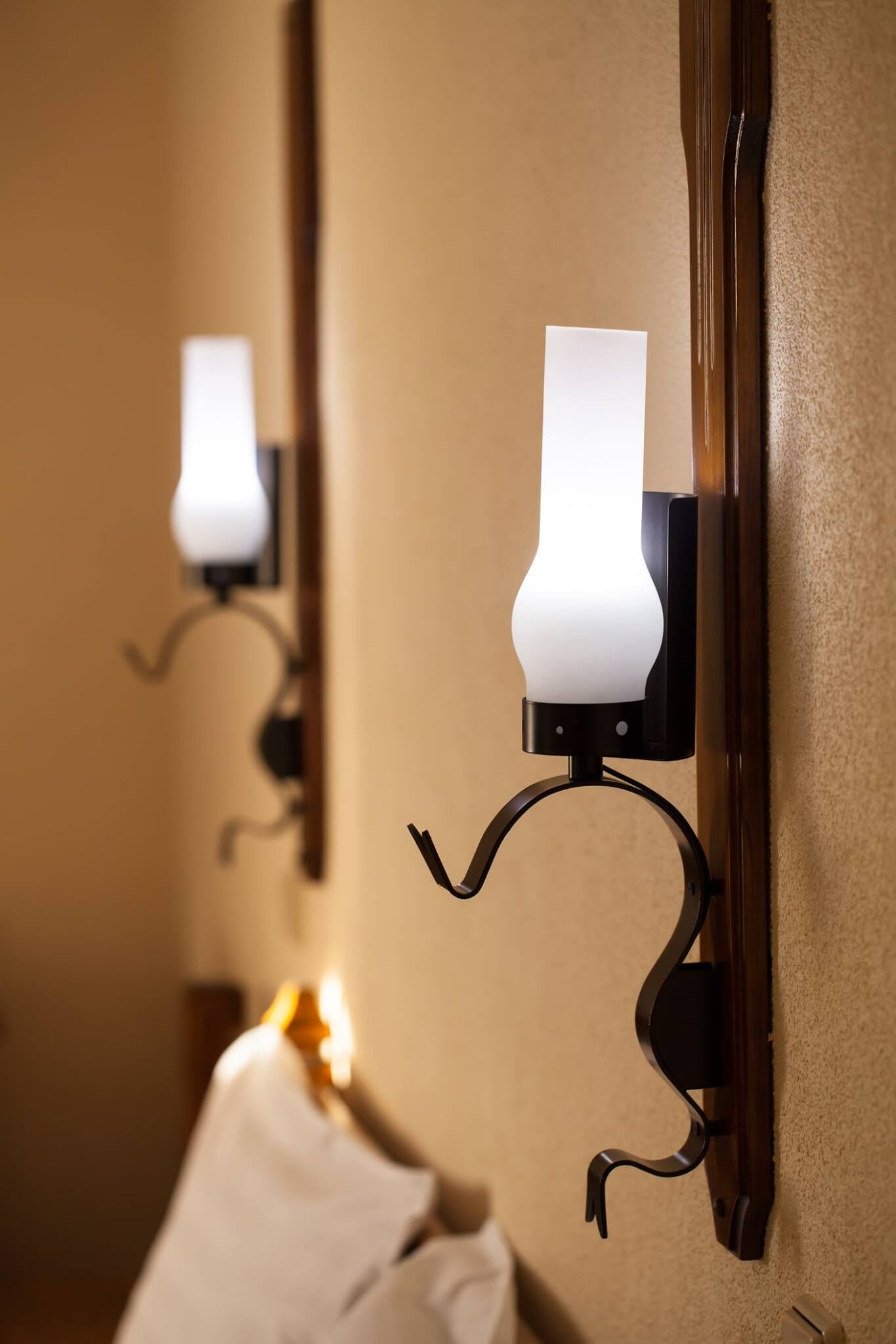 Un pasillo con apliques de pared y un espejo que refleja la luz.