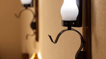 Un pasillo con apliques de pared y un espejo que refleja la luz.