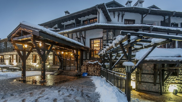 Un bâtiment enneigé, doté d’un escalier en bois et d’un espace extérieur aménagé avec des sièges.