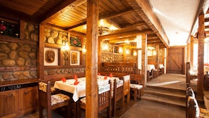 Un intérieur rustique avec des murs en pierre, des bancs en bois et des tables dressées pour le repas.