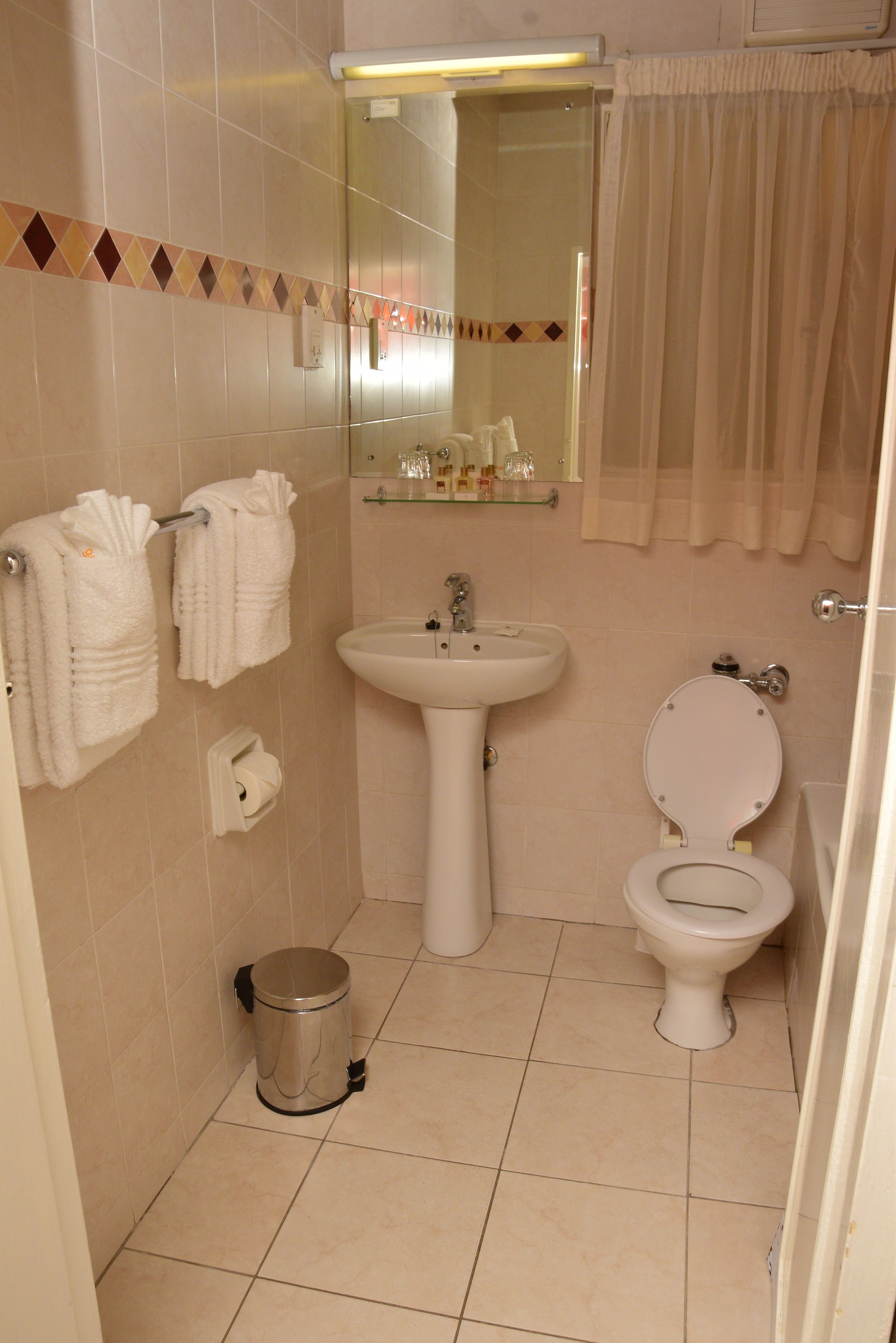 A bathroom with a sink, toilet, and a trash can.