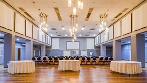 Uma sala de conferência com uma mesa comprida, várias cadeiras e uma tela grande na frente.