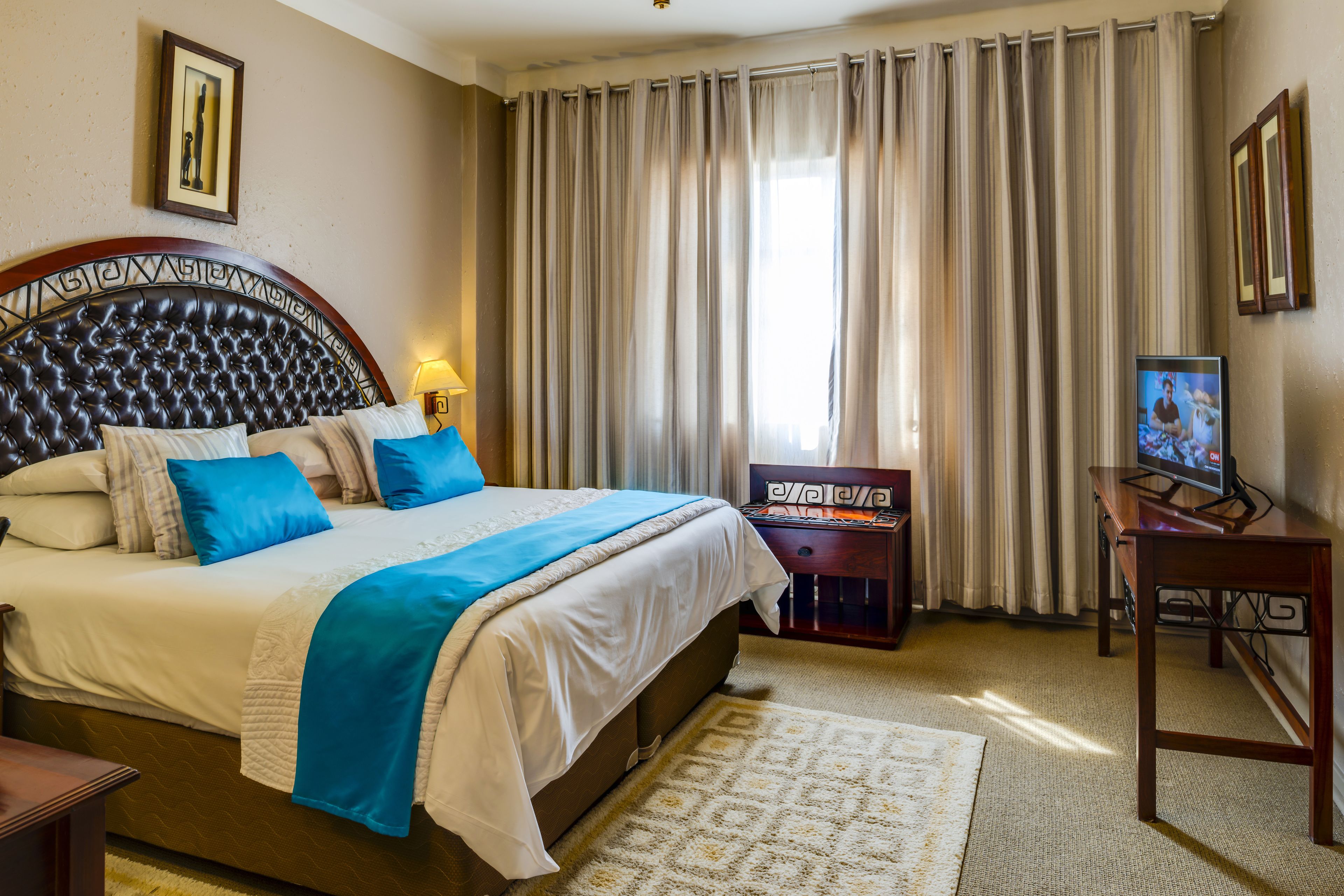 Een hotelkamer met een groot bed, een televisie en gordijnen.