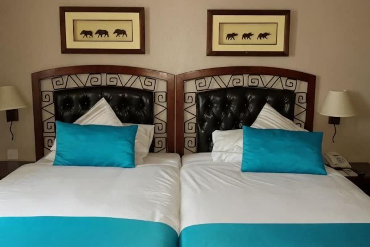 Two adjacent beds with headboards featuring a geometric pattern, white bedding, and blue pillows.