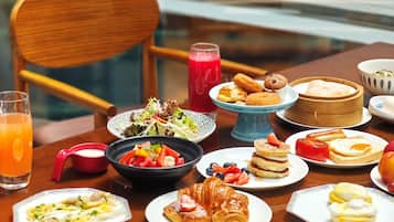 Une table à manger avec divers aliments pour le petit-déjeuner, notamment des œufs, des viennoiseries et une salade.