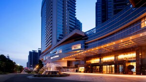 A modern hotel with a prominent water feature in front, large glass windows, and a well-lit entrance. - Hilton Foshan (Foshan)