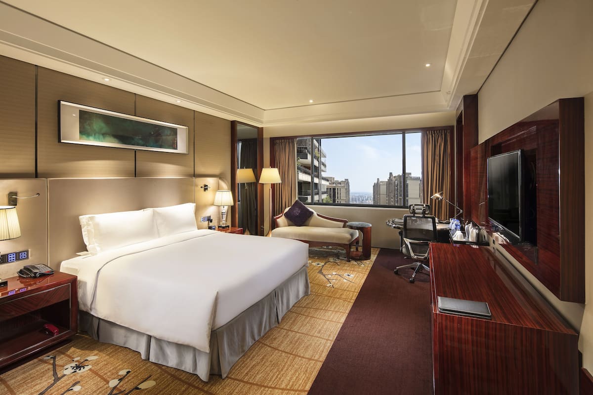 Una habitación de hotel con una cama grande, un escritorio, un televisor y vistas a la ciudad.