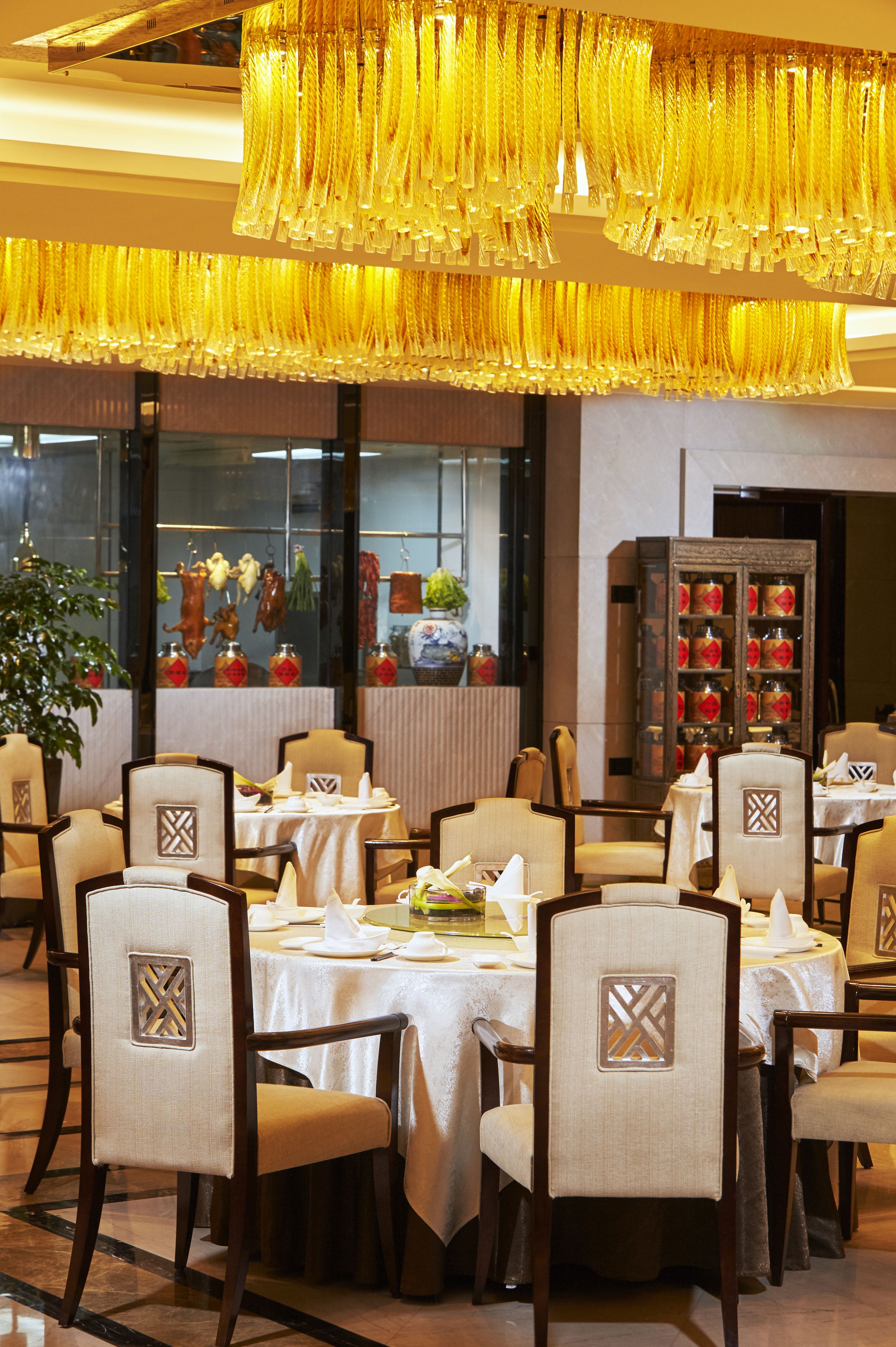 A dining area with round tables, chairs, and a decorative chandelier.