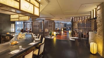 A modern dining area with a long table, chairs, and a decorative ceiling.
