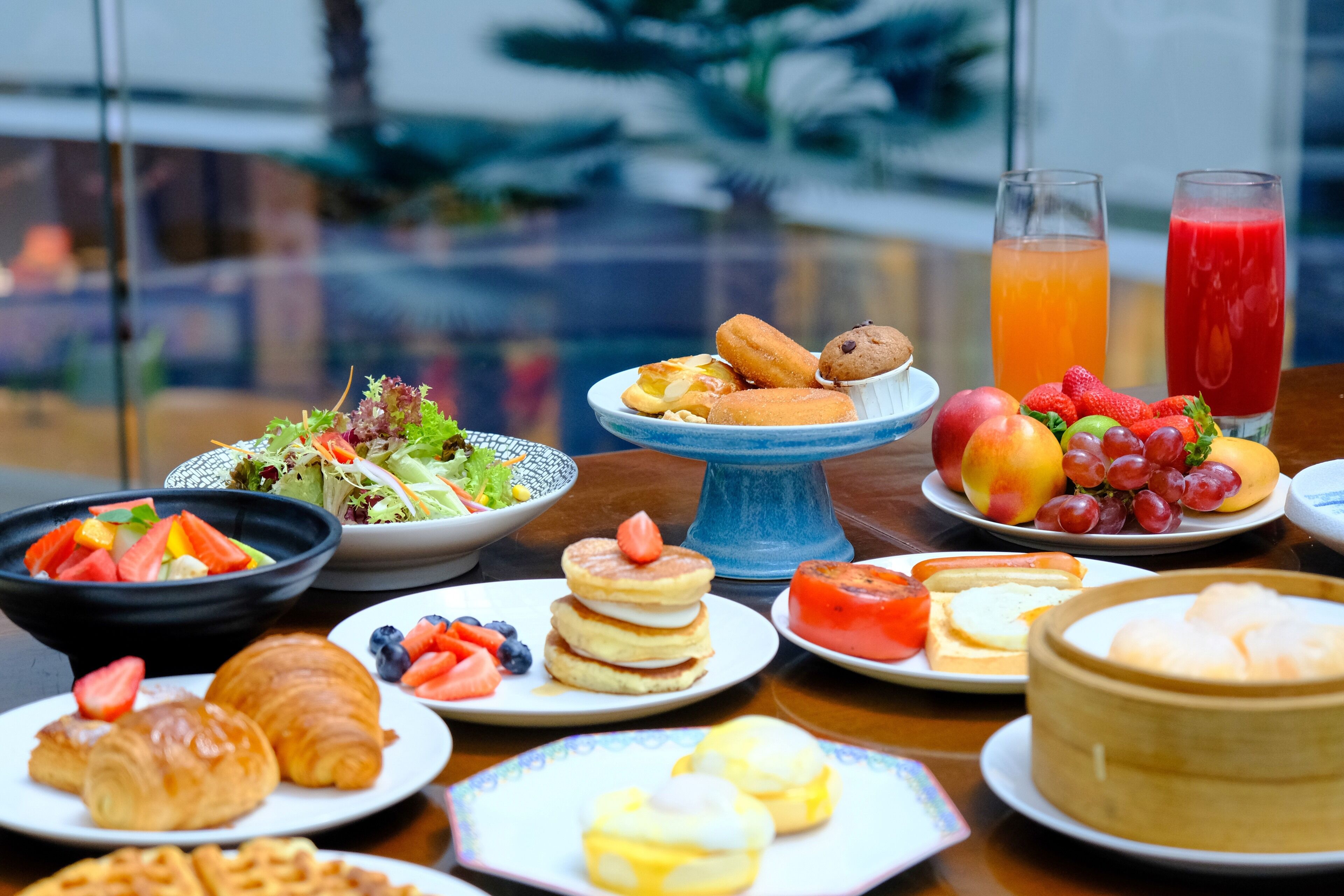 A breakfast buffet with various dishes, including pastries, fruits, and a fruit salad.