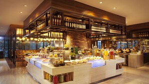 A buffet setup with various food items and beverages, a wooden bar area with bottles, and a seating area with tables and chairs. - Hilton Foshan (Foshan)
