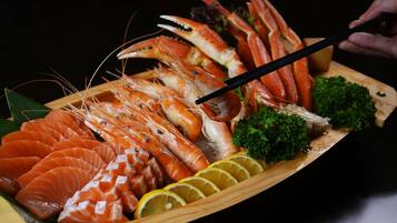 A wooden tray with various seafood including prawns and salmon, garnished with lemon slices and parsley.