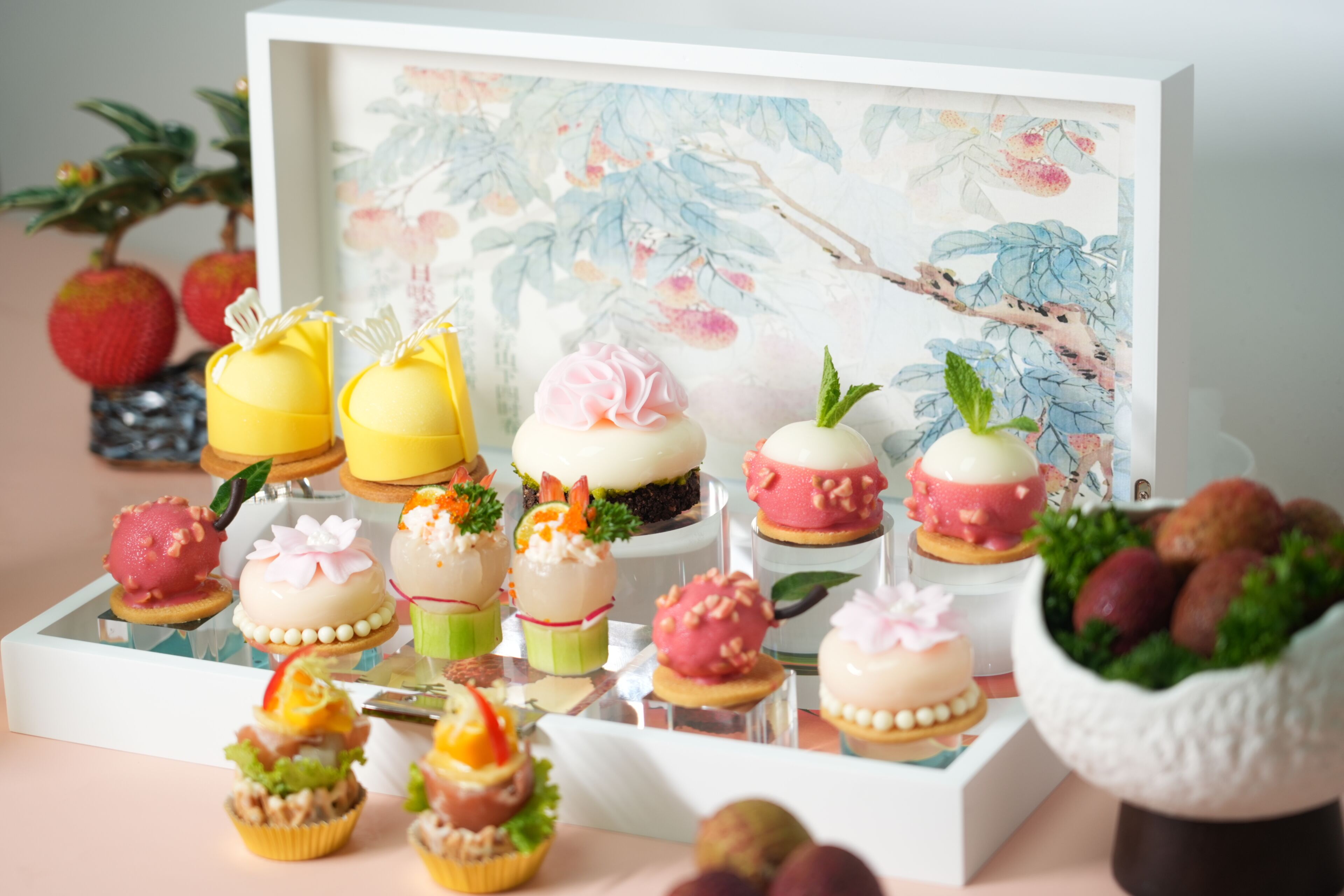 A variety of desserts displayed in a white box with a floral background.