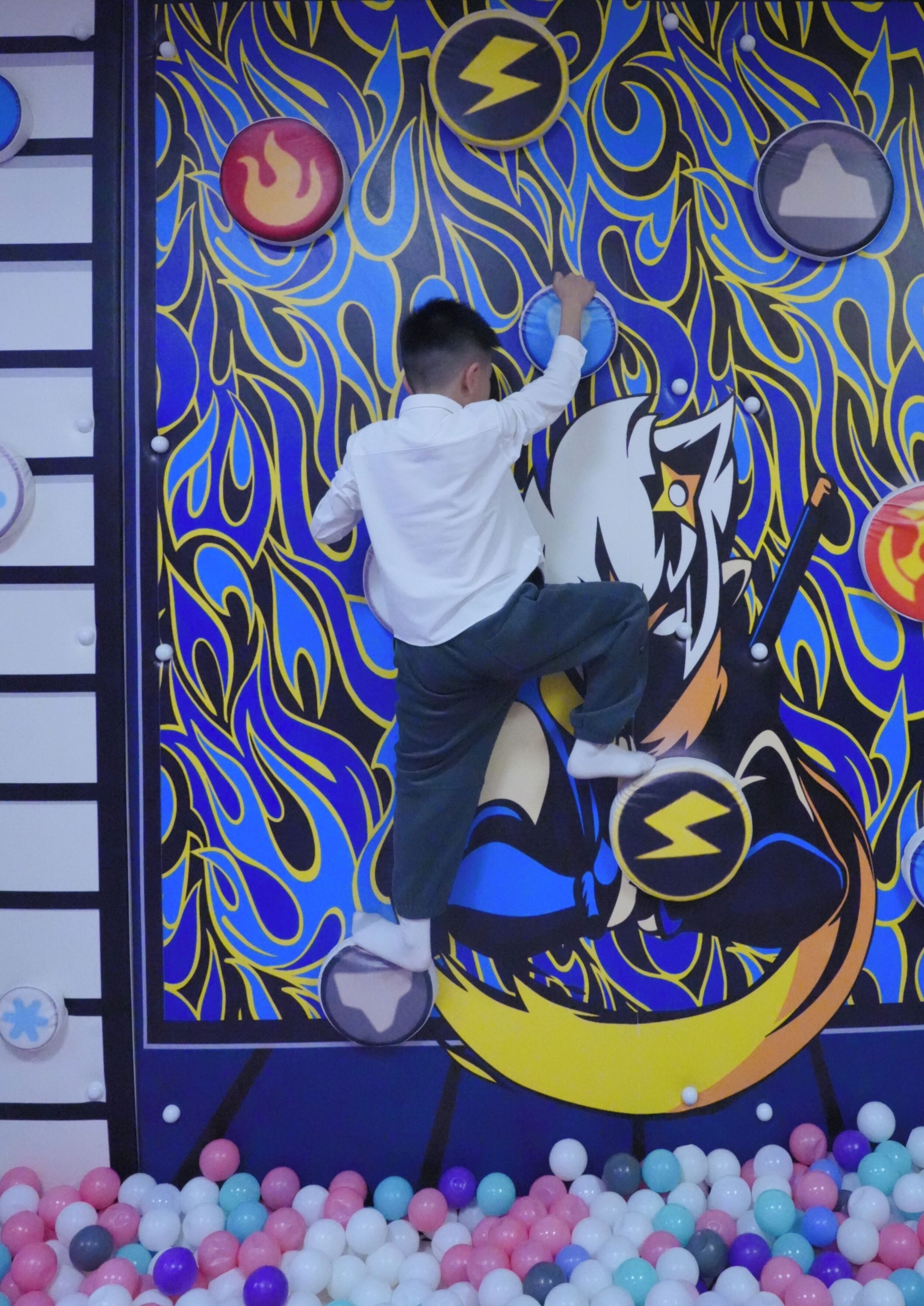 A child climbing a colorful wall with a dragon design.