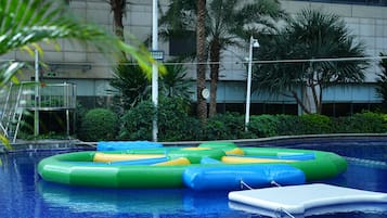 Una piscina techada, una piscina al aire libre, sombrillas