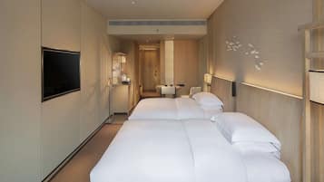 A hotel room with two beds, a TV, a desk, and a bathroom.