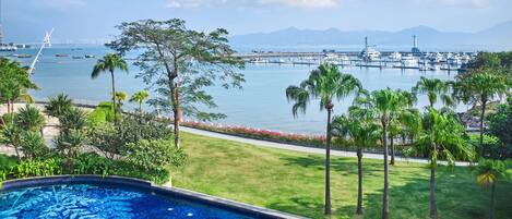 A swimming pool with a view of a marina and distant mountains.