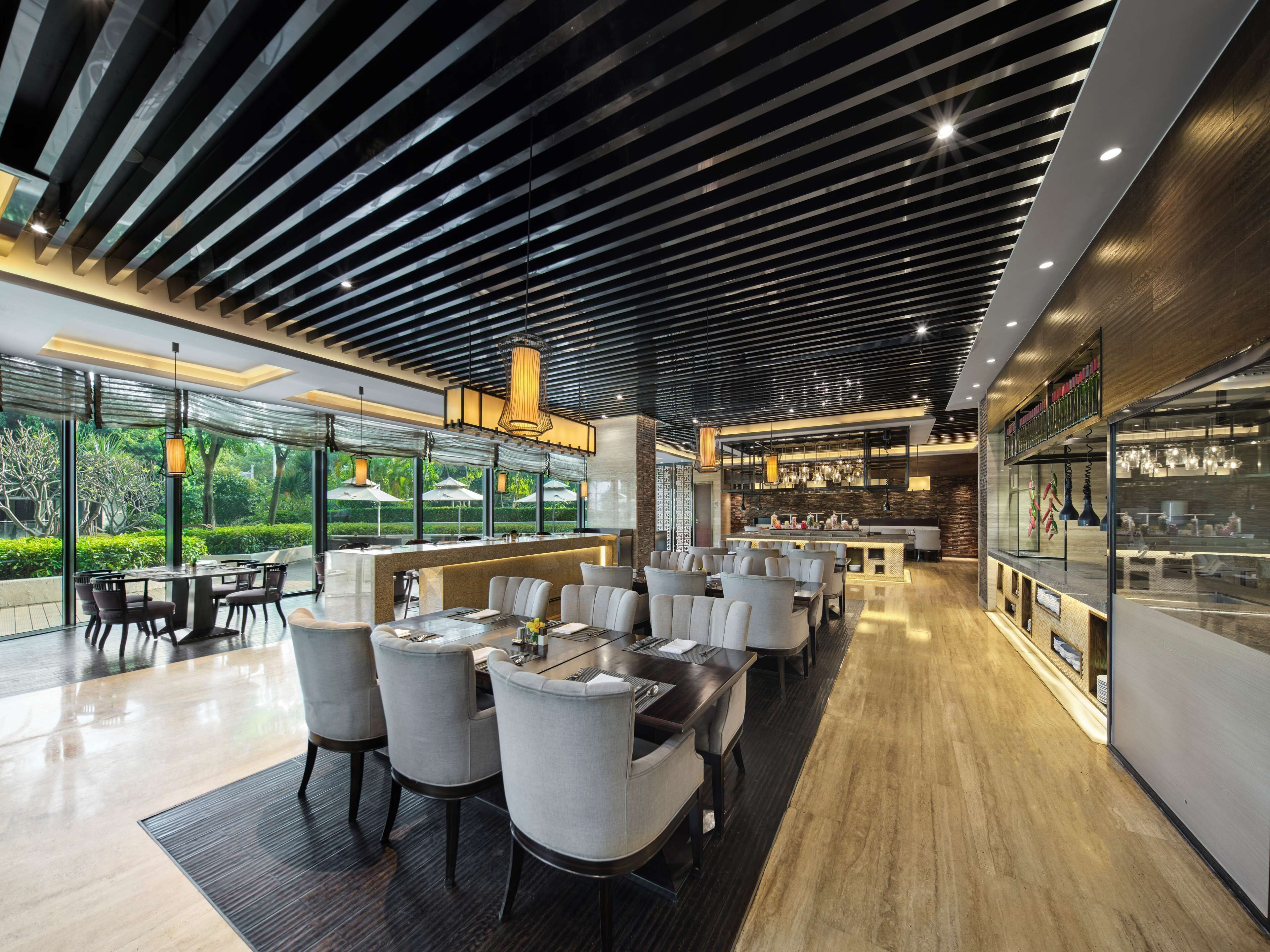 A modern restaurant with a bar area, seating, and a view of greenery.