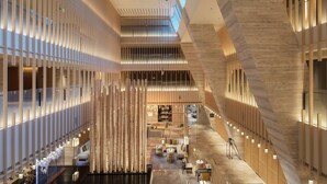 Een ruime lobby met een centraal atrium, moderne inrichting en een bar.