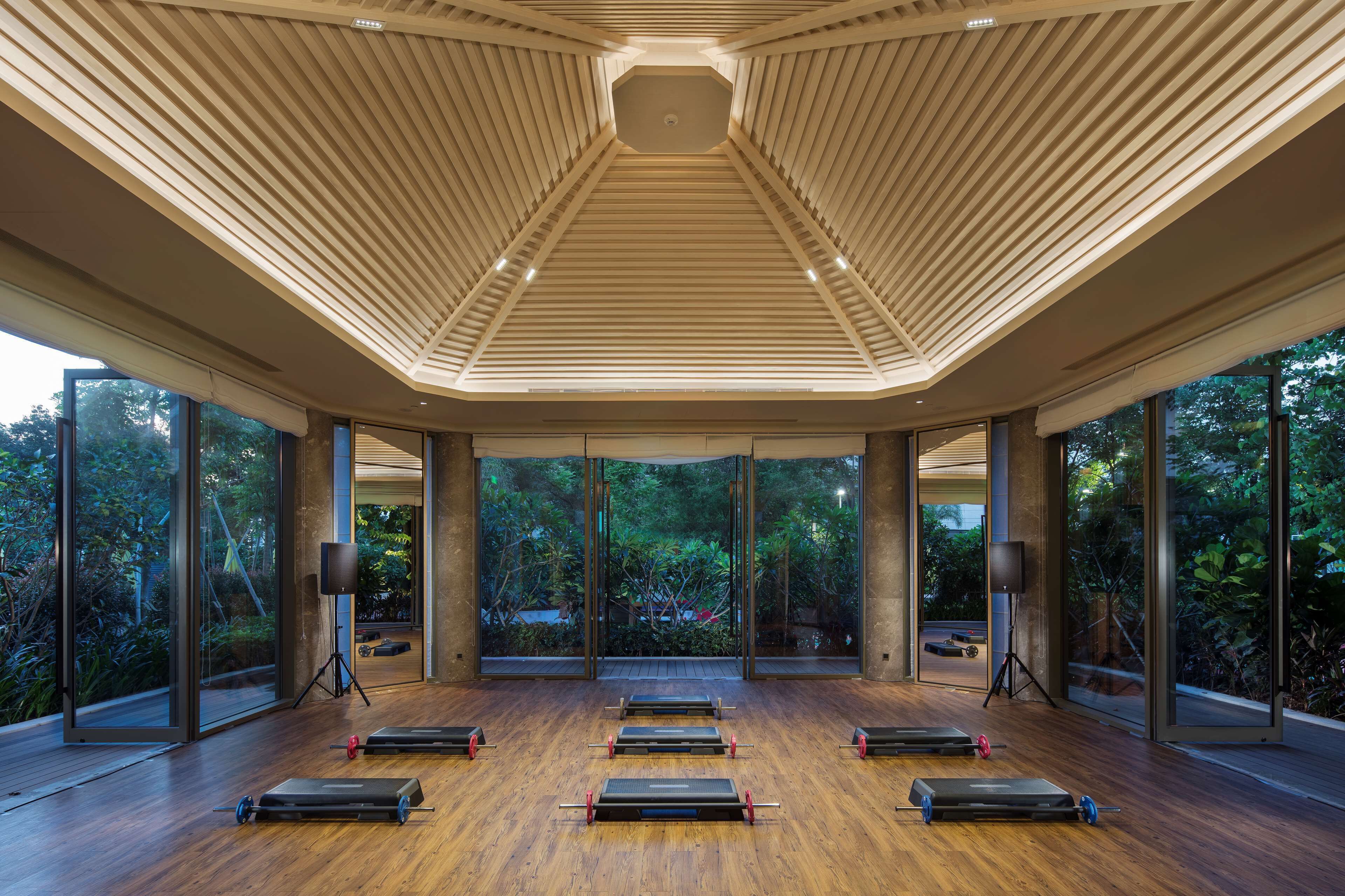 Une pièce spacieuse dotée d’un plancher en bois, de grandes fenêtres et d’appareils de musculation.