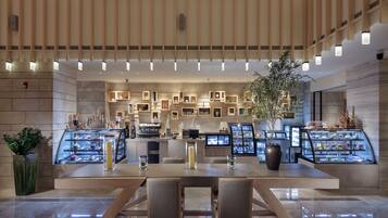 A modern hotel lobby with a central bar area, seating, and a decorative plant.