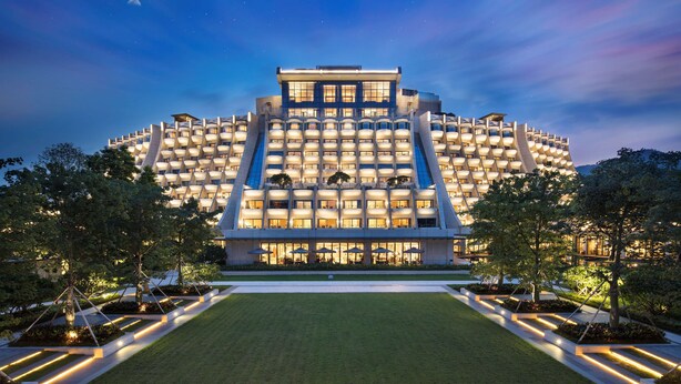 Een modern hotel met een uniek, circulair ontwerp, met meerdere balkons en een goed verlichte gevel.