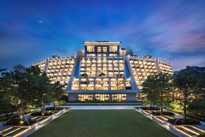 Un hotel moderno con un diseño circular único, que cuenta con varios balcones y una fachada bien iluminada.