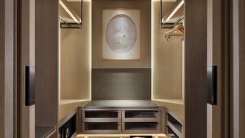 A walk-in closet with wooden doors, a recessed bench, and a framed artwork on the back wall.