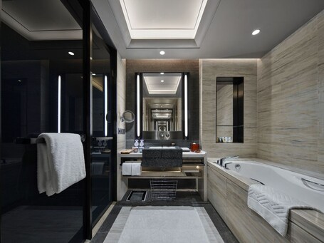 A modern bathroom with a large mirror, a bathtub, and a vanity with a sink.