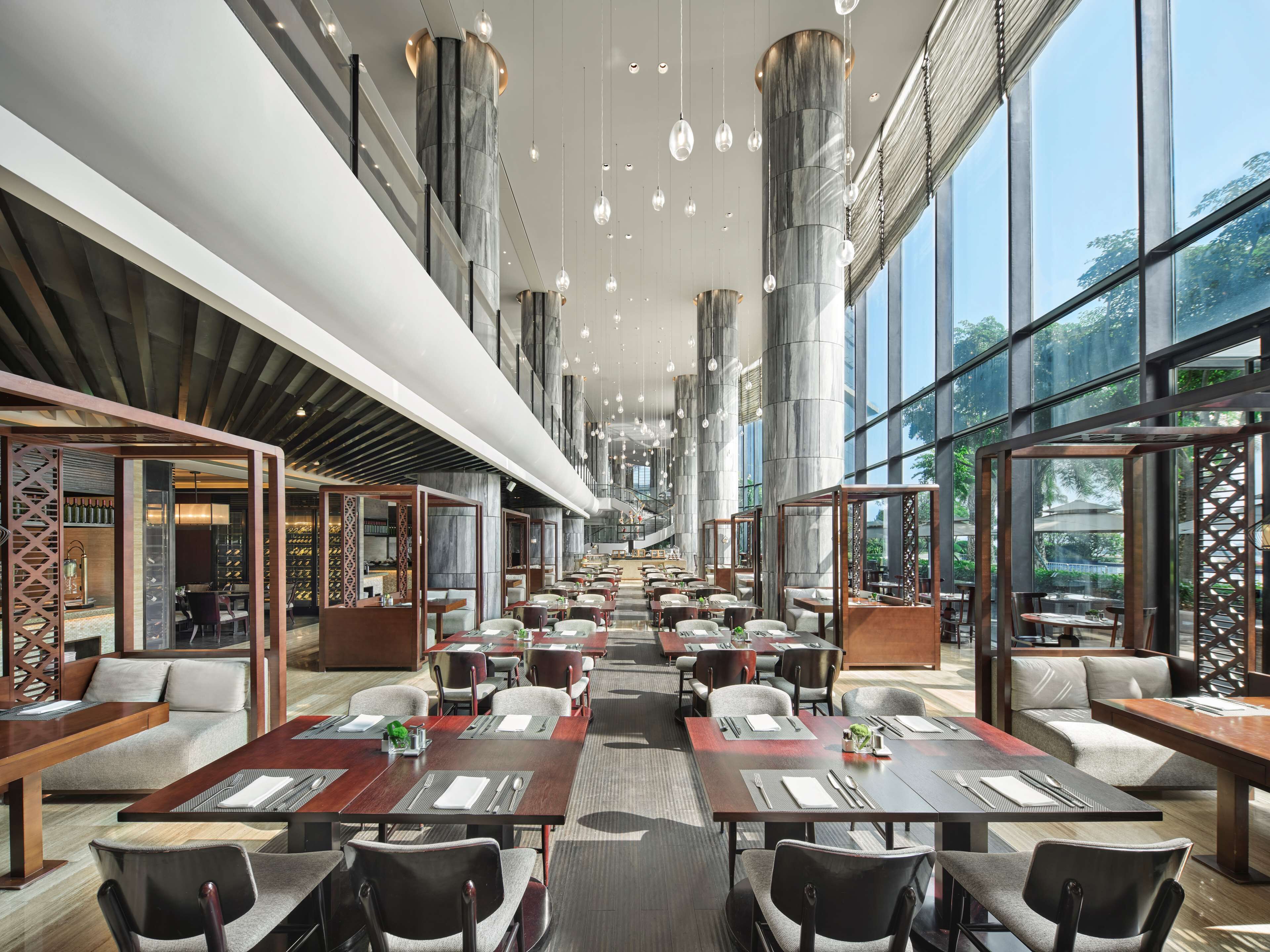 Un restaurant spacieux avec de hauts plafonds, de grandes fenêtres et un éclairage moderne.
