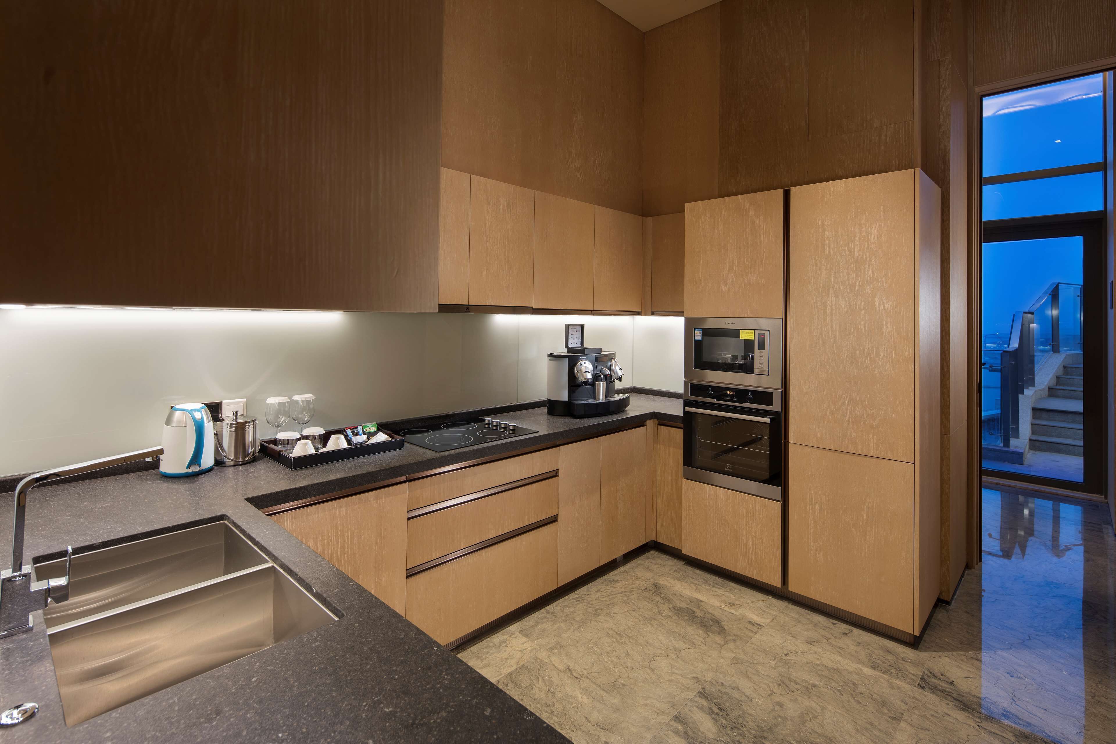 Une cuisine moderne dotée d’appareils électroménagers en acier inoxydable, de meubles en bois et d’une grande fenêtre offrant une vue sur l’extérieur.