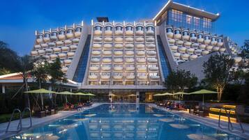 Een modern hotel met een uniek architectuurontwerp, met een groot zwembad en buitenzitplaatsen.