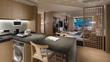 A modern kitchen with a built-in washer, a central island with bar stools, and a view of a balcony with outdoor seating.