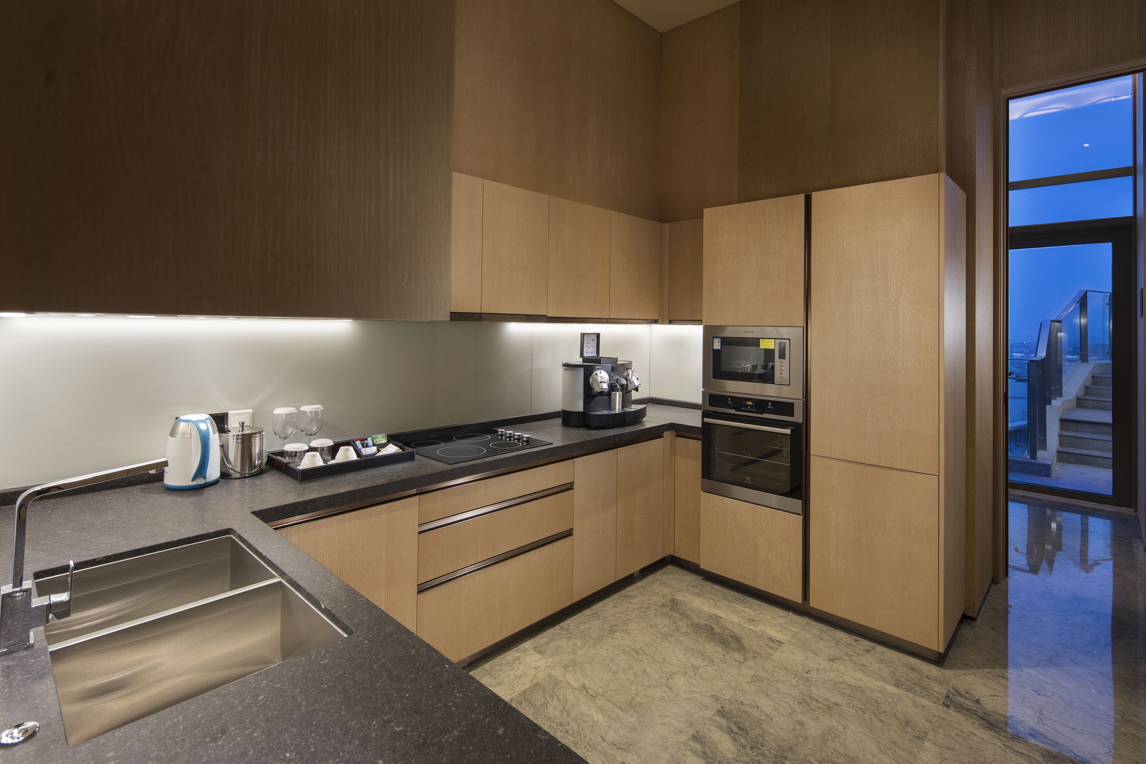 Una cocina moderna con un lavamanos de acero inoxidable, una cafetera y un horno empotrado.