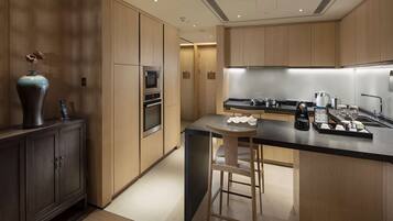 A modern kitchen with wooden cabinets, a built-in oven, a microwave, and a coffee maker.
