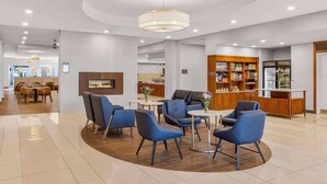 Eine moderne Lobby mit Sitzbereichen, einem Kamin und einer Theke für Verpflegung.