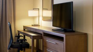 Ein Hotelzimmer mit einem Holztisch, einem Fernseher, einem Sessel und einer Lampe.
