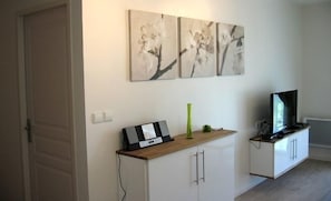 A modern living room with a flat-screen TV, a wooden console table, and three abstract paintings on the wall. - Résidence le Beau Site (Capvern)