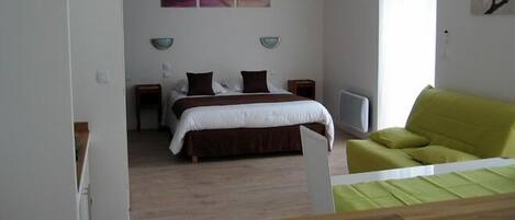 A bedroom with a bed, bedside tables, a green sofa, and abstract wall art.