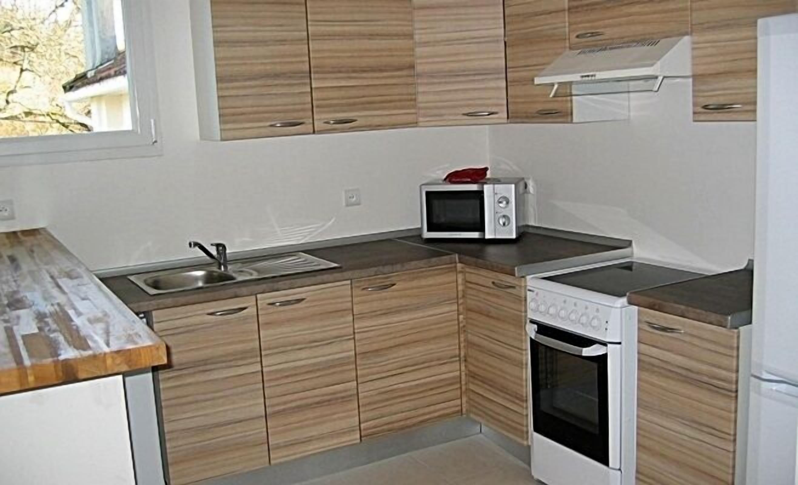 A kitchen with wooden cabinets, a microwave, a stove, and a sink.